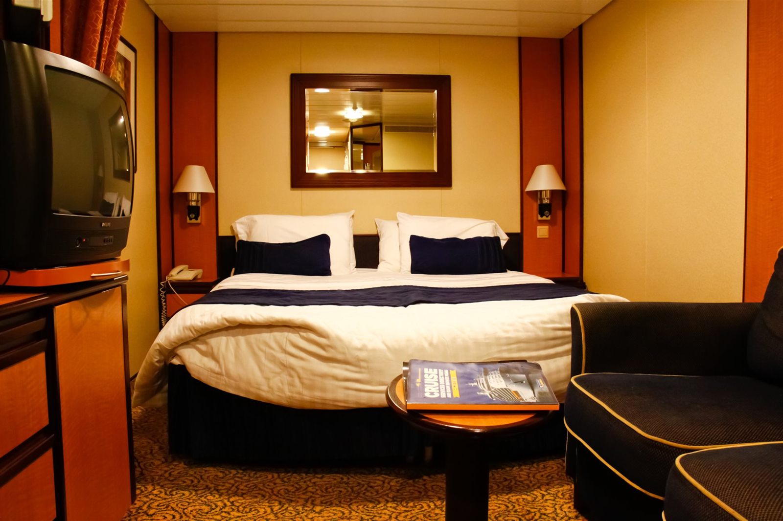 Cruise ship cabin with a double bed, sofa and wall mirror